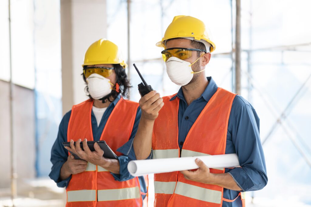 colleagues-with-safety-equipment-working-with-blueprints